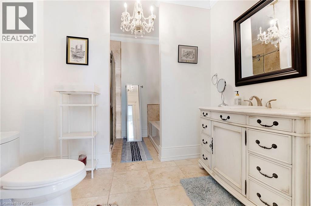 Bathroom featuring a distressed white vanity with dark hardware, a rectangular mirror, and a crystal chandelier - 6195 Milburough Line, Burlington, ON - Indoor Photo Showing Bathroom