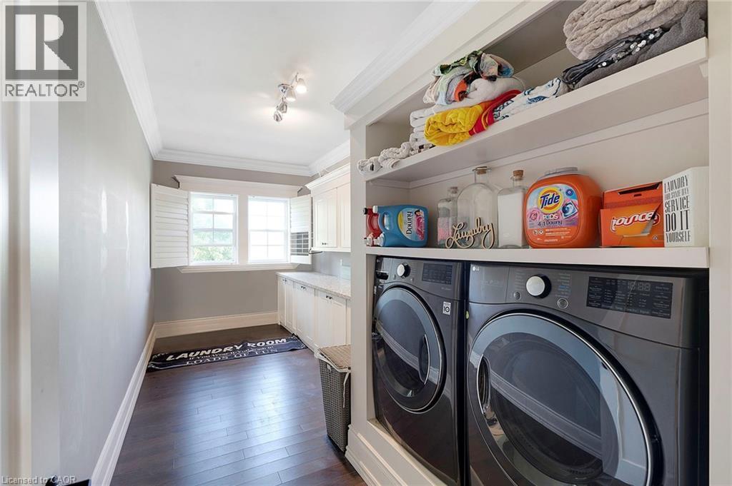 Laundry area featuring wood-finish flooring, white shaker cabinetry, and a light-toned countertop - 6195 Milburough Line, Burlington, ON - Indoor Photo Showing Laundry Room