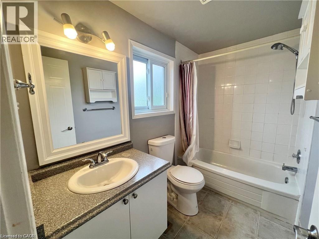 Bathroom featuring a white vanity with a speckled countertop, an oval undermount sink, and a chrome faucet - 209 Auburn Drive Unit# A, Waterloo, ON