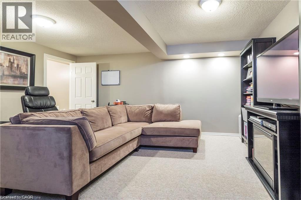Carpeted recreation room featuring neutral wall tones, recessed lighting, and a built-in media console with shelving - 209 Auburn Drive Unit# A, Waterloo, ON