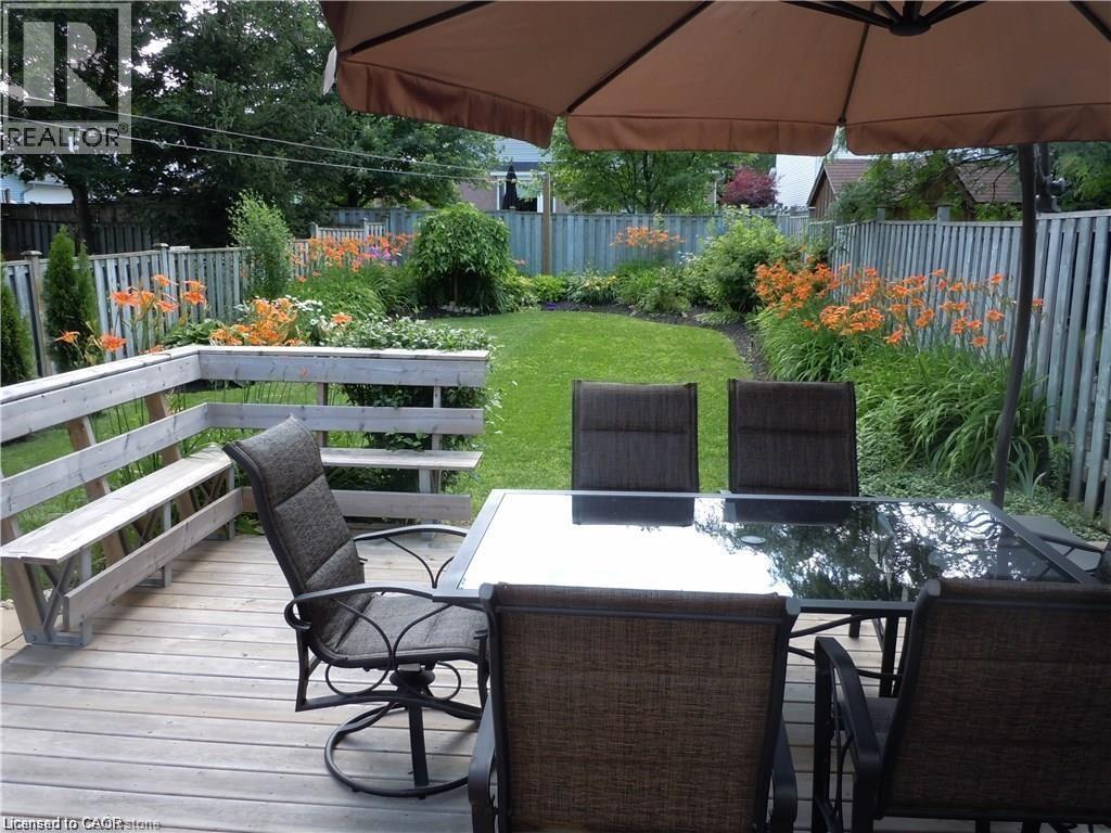 Wood-finish deck featuring a built-in bench, offering direct access to the manicured lawn and garden beds - 209 Auburn Drive Unit# A, Waterloo, ON