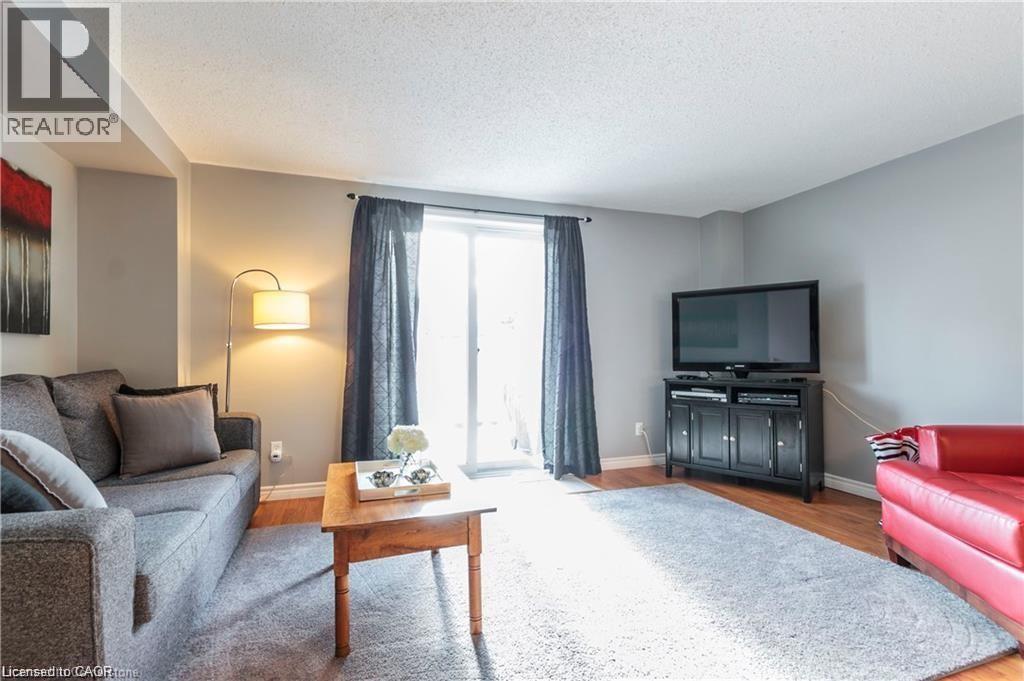 Living area featuring wood-finish flooring, light grey painted walls, and a white ceiling - 209 Auburn Drive Unit# A, Waterloo, ON