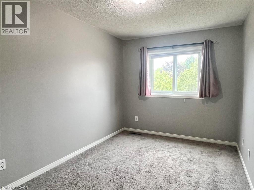 Room featuring neutral gray walls and gray carpeting - 209 Auburn Drive Unit# A, Waterloo, ON