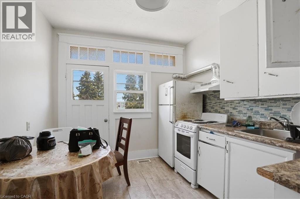Kitchen space featuring white cabinetry, a mosaic tile backsplash, and a wood-finish floor - 744 Queen Street S, Kitchener, ON