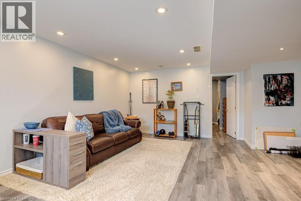 Spacious living area featuring light gray walls, recessed ceiling lighting, wood-finish flooring, and a large area rug - 61 Ditner Avenue, Baden, ON - Indoor