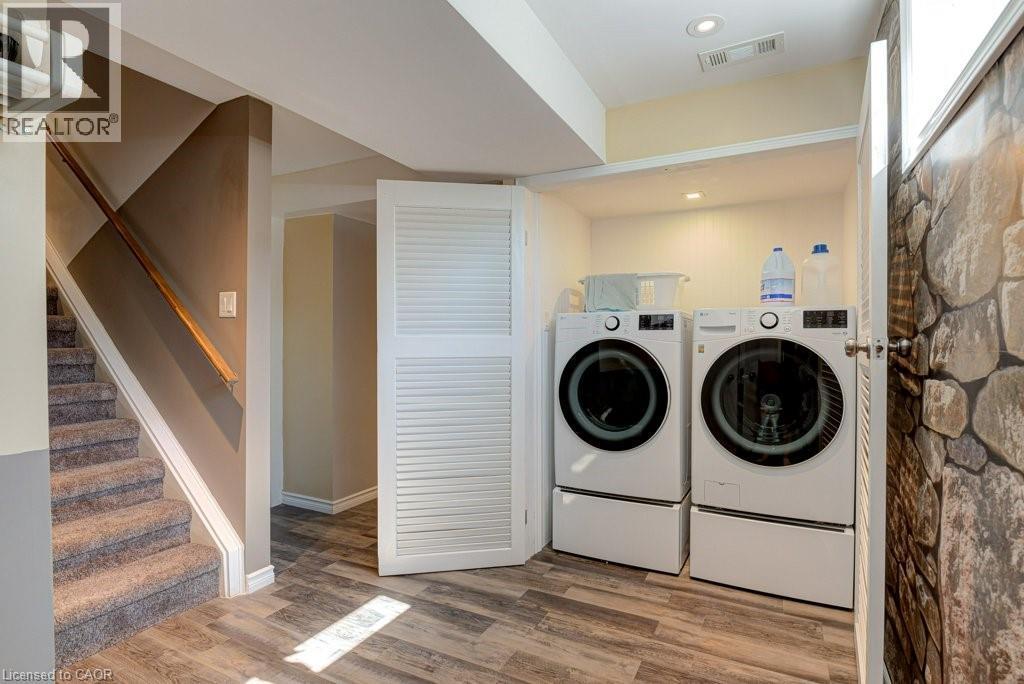 Dedicated laundry area featuring a white front-loading washer and dryer set with pedestals, recessed lighting, and a bi-fold louvered door - 61 Ditner Avenue, Baden, ON - Indoor Photo Showing Laundry Room