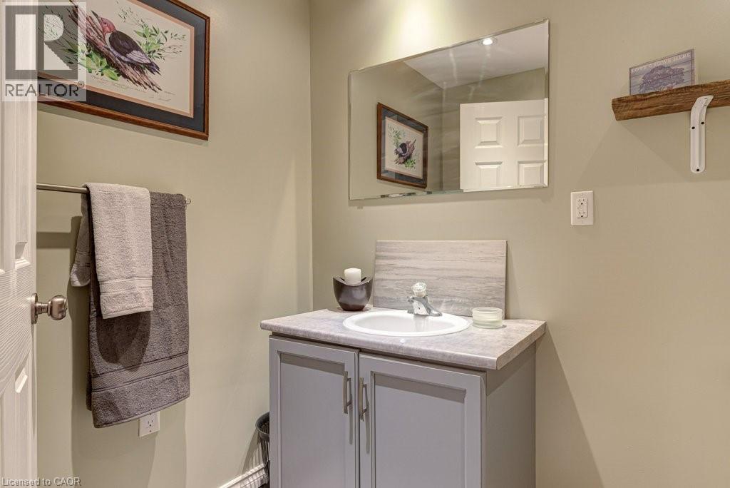Powder room featuring a single vanity with a white basin and light-toned countertop, complemented by a rectangular wall-mounted mirror - 61 Ditner Avenue, Baden, ON - Indoor Photo Showing Bathroom