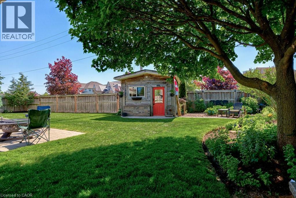 Expansive green lawn featuring a paver patio area, mature shade tree, and established perimeter plantings - 61 Ditner Avenue, Baden, ON - Outdoor