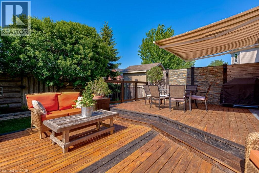 Multi-level wood deck featuring a retractable awning, stacked stone accent wall, and perimeter privacy fencing - 61 Ditner Avenue, Baden, ON - Outdoor With Deck Patio Veranda With Exterior