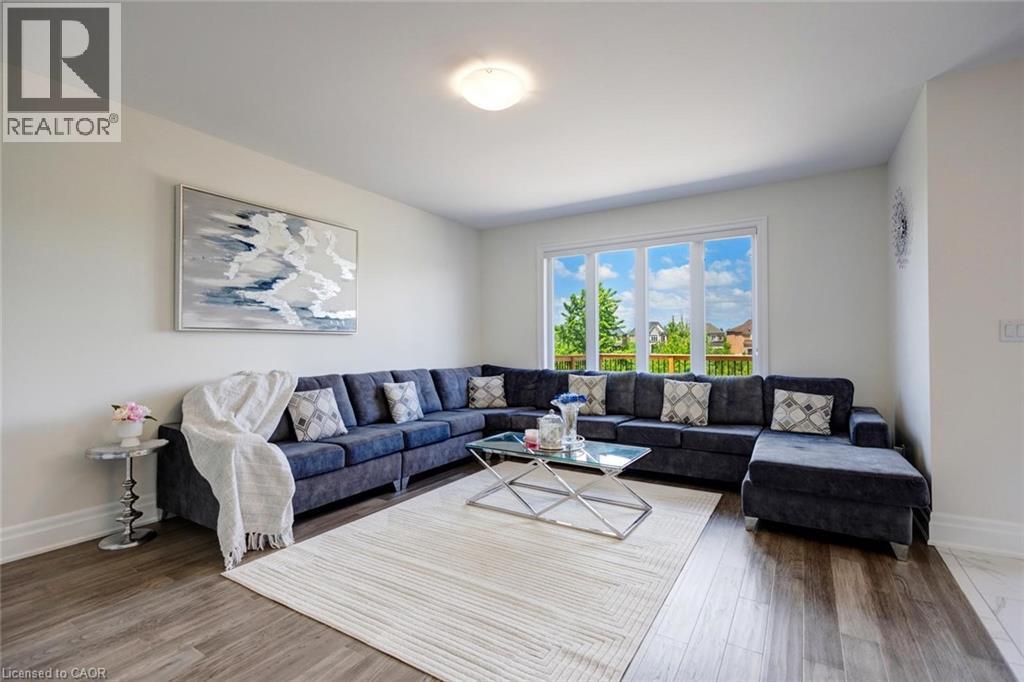 Bright living space featuring wood-finish flooring and a multi-pane window - 57 Hollybrook Trail, Kitchener, ON