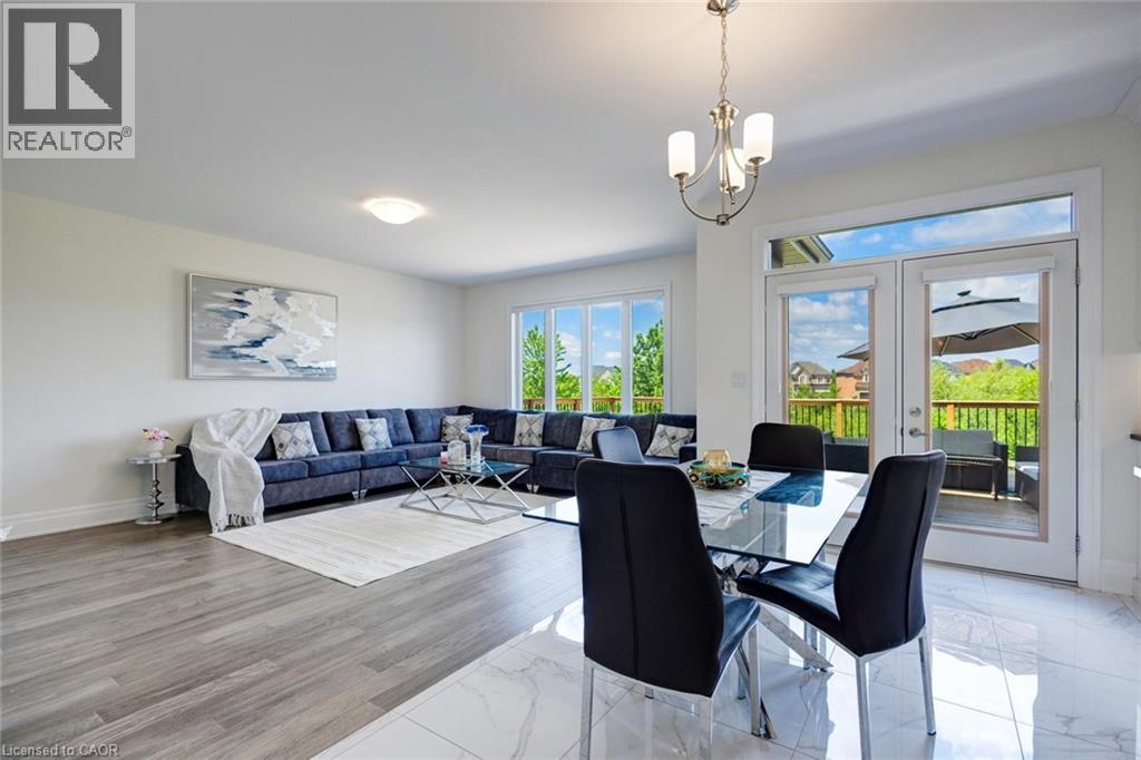 Open-concept living and dining area featuring wood-finish flooring in the living space and polished tile in the dining area - 57 Hollybrook Trail, Kitchener, ON