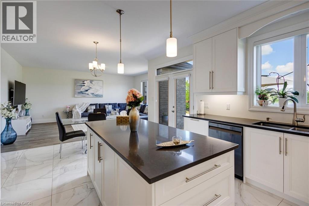 Kitchen featuring a large central island with dark countertop, white cabinetry with contemporary hardware, and undermount sink with a gooseneck faucet - 57 Hollybrook Trail, Kitchener, ON