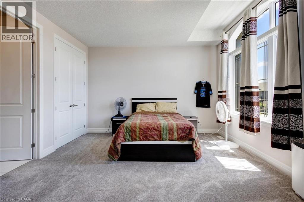 Bedroom featuring light grey carpet flooring, white walls, and a multi-pane window with an arched top - 57 Hollybrook Trail, Kitchener, ON