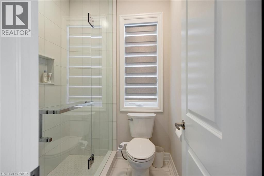 Glass-enclosed shower featuring white subway tile, a recessed shower niche, and a contrasting small hexagonal tile shower floor - 57 Hollybrook Trail, Kitchener, ON