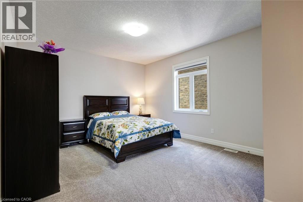 Spacious room with light neutral wall tones, textured ceiling, and gray carpeting - 57 Hollybrook Trail, Kitchener, ON