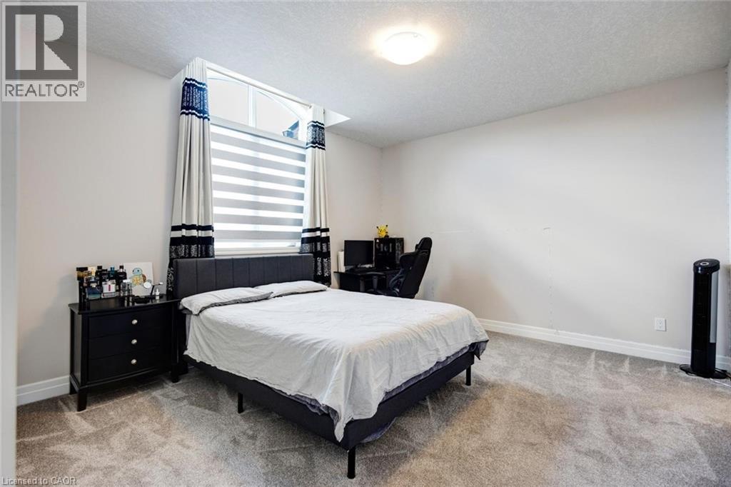 Spacious room with plush gray carpeting, neutral wall finishes, and a contemporary window featuring layered blinds and decorative drapes - 57 Hollybrook Trail, Kitchener, ON