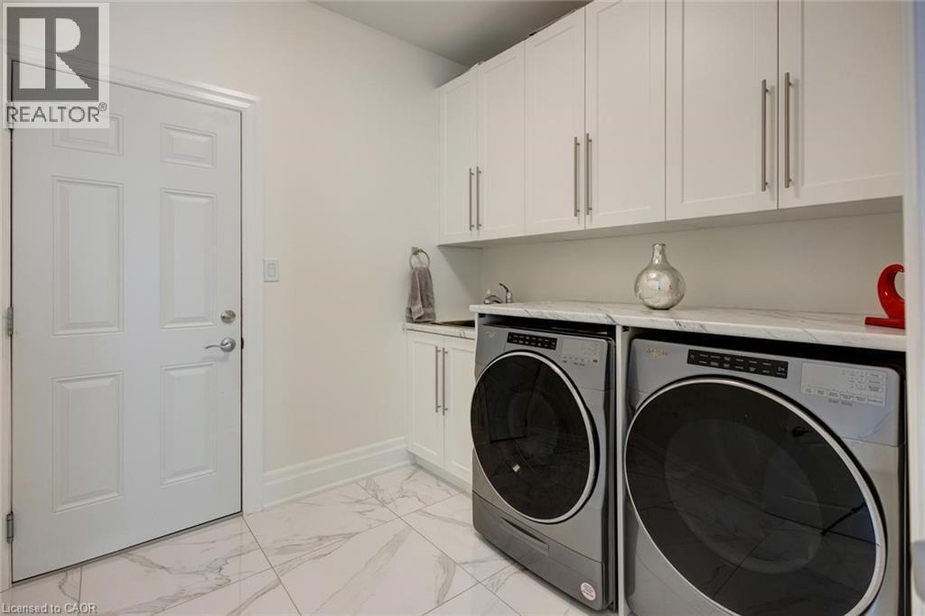Dedicated laundry area featuring white cabinetry, a built-in sink, and a countertop - 57 Hollybrook Trail, Kitchener, ON