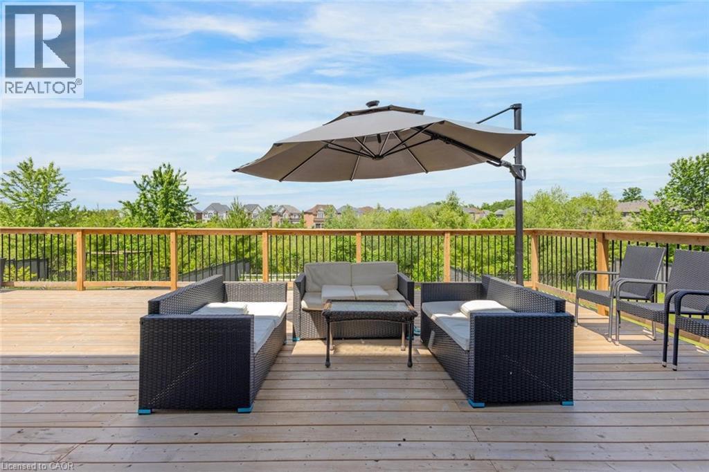 Expansive wooden deck featuring horizontal planking and a natural wood railing with black metal balusters - 57 Hollybrook Trail, Kitchener, ON
