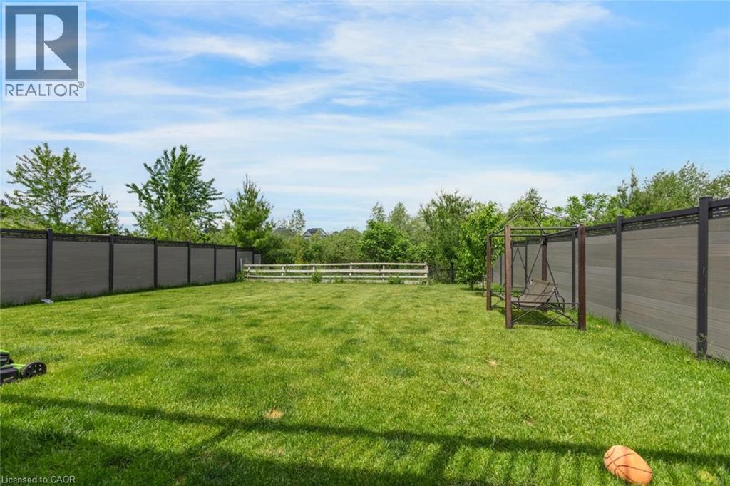 Expansive green lawn framed by a composite panel fence and a white split-rail fence - 57 Hollybrook Trail, Kitchener, ON
