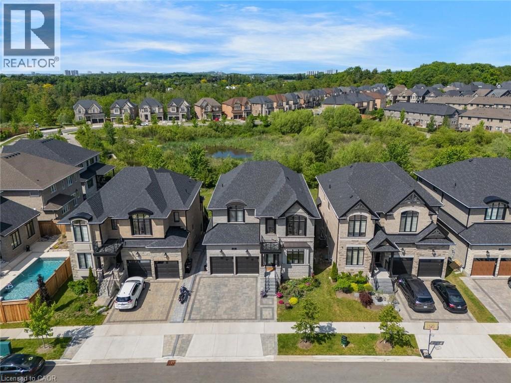 Modern residential streetscape featuring properties with stone and stucco exteriors, dark shingle roofs, and paved driveways - 57 Hollybrook Trail, Kitchener, ON