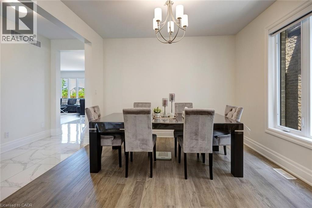 Dining area featuring wood-finish flooring, a contemporary chandelier, and a large window with white trim - 57 Hollybrook Trail, Kitchener, ON