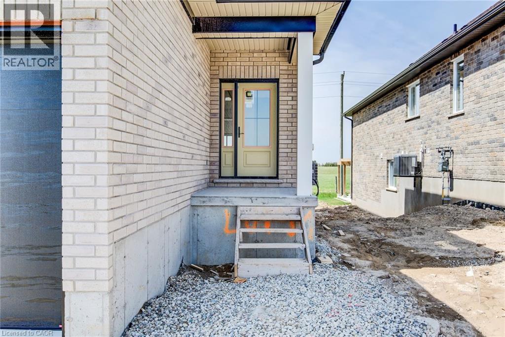Main entrance featuring a covered porch with a white column, a light-colored entry door with windowpanes, and a concrete landing - 114 Bedell Drive, Mapleton, ON - Outdoor With Exterior