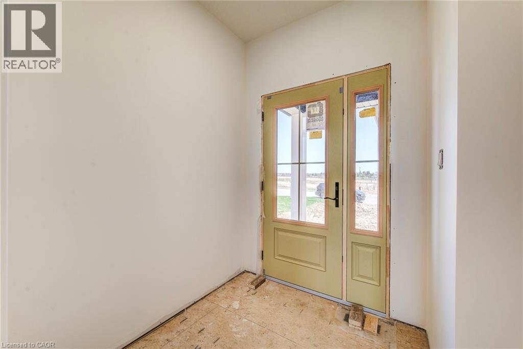 Entryway featuring a single-panel door with glass inserts and an adjacent fixed glass panel, light-colored walls, and subflooring - 114 Bedell Drive, Mapleton, ON - Indoor Photo Showing Other Room