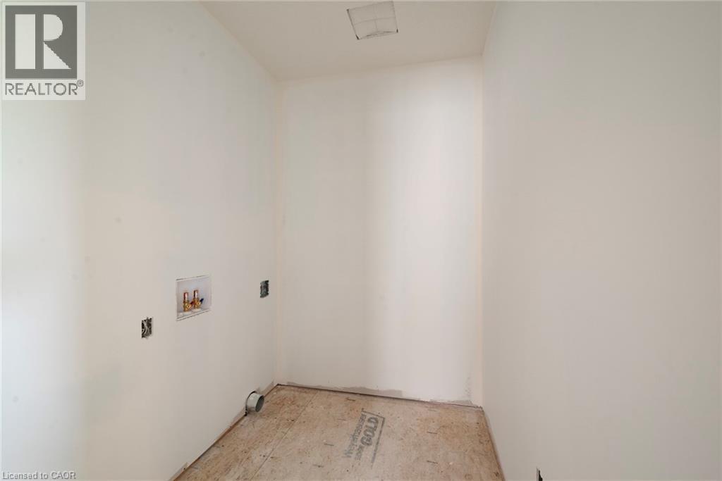 Dedicated utility space with white walls, rough plywood subfloor, and exposed plumbing connections - 114 Bedell Drive, Mapleton, ON - Indoor Photo Showing Other Room