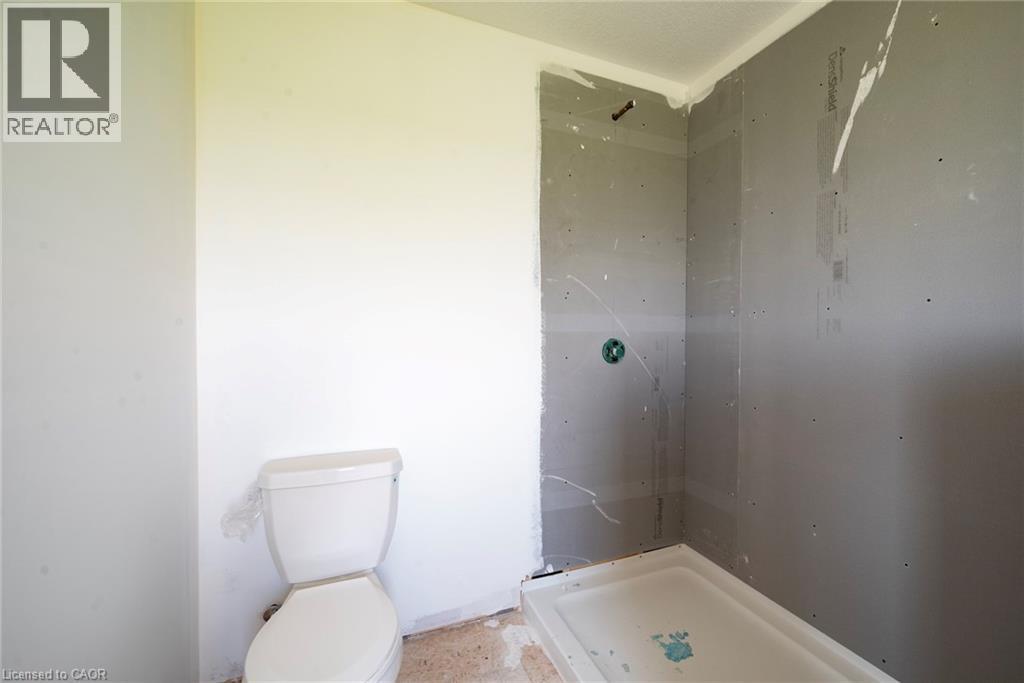 Bathroom featuring a white toilet and a shower stall with a pre-formed base - 114 Bedell Drive, Mapleton, ON - Indoor Photo Showing Bathroom