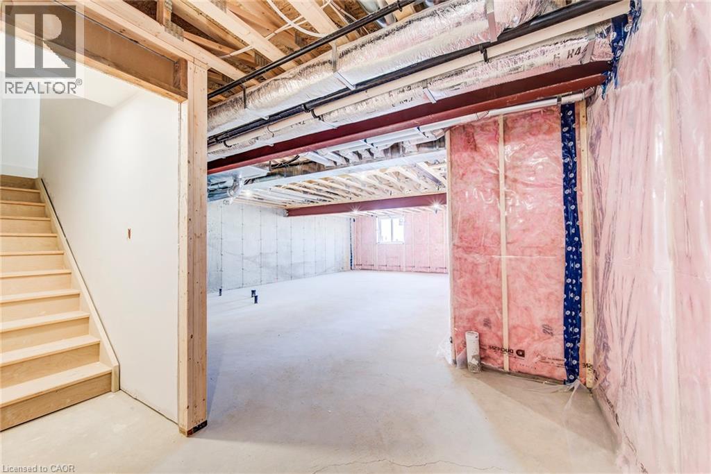 Unfinished basement offering expansive concrete flooring, exposed ceiling joists, structural steel beams, and partial insulation - 114 Bedell Drive, Mapleton, ON - Indoor Photo Showing Other Room