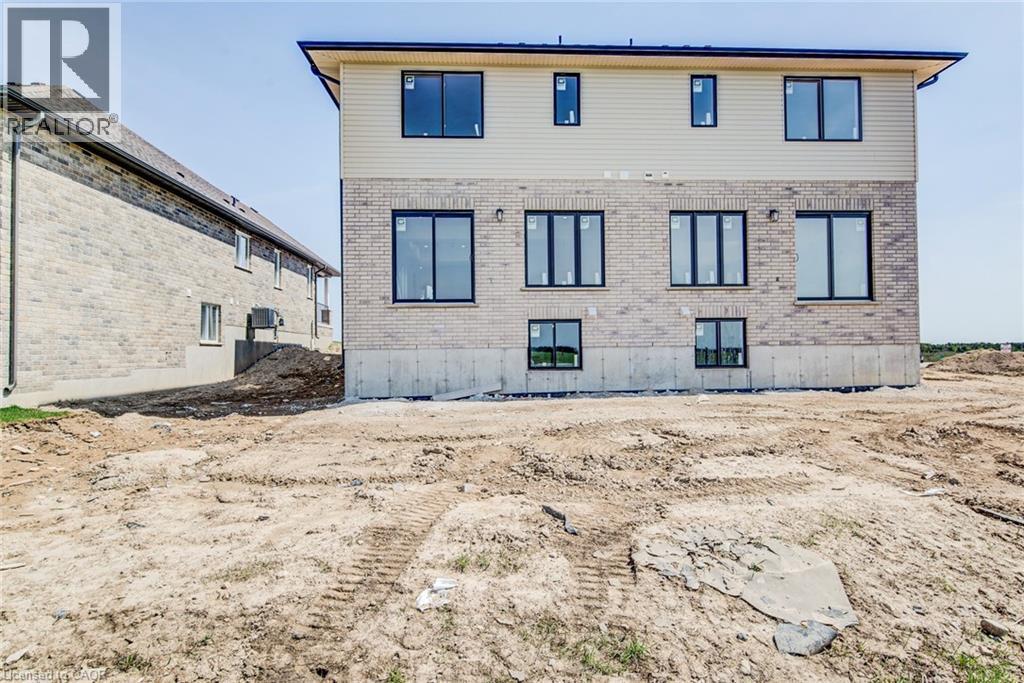 Rear exterior showcasing brick and siding facade with multiple black-framed windows - 114 Bedell Drive, Mapleton, ON - Outdoor With Exterior