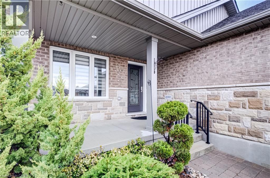 View of exterior entry featuring a porch, stone siding, board and batten siding, and brick siding - 130 Bridge Crescent, Minto, ON