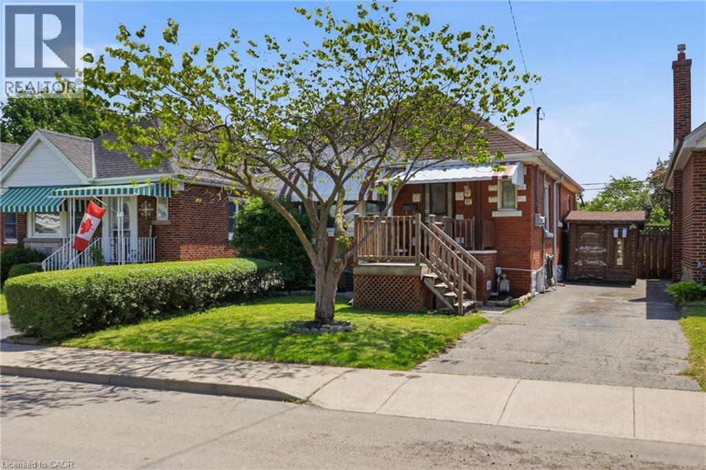 Red brick exterior with white trim details and a covered porch entry - 97 Tragina Avenue S, Hamilton, ON