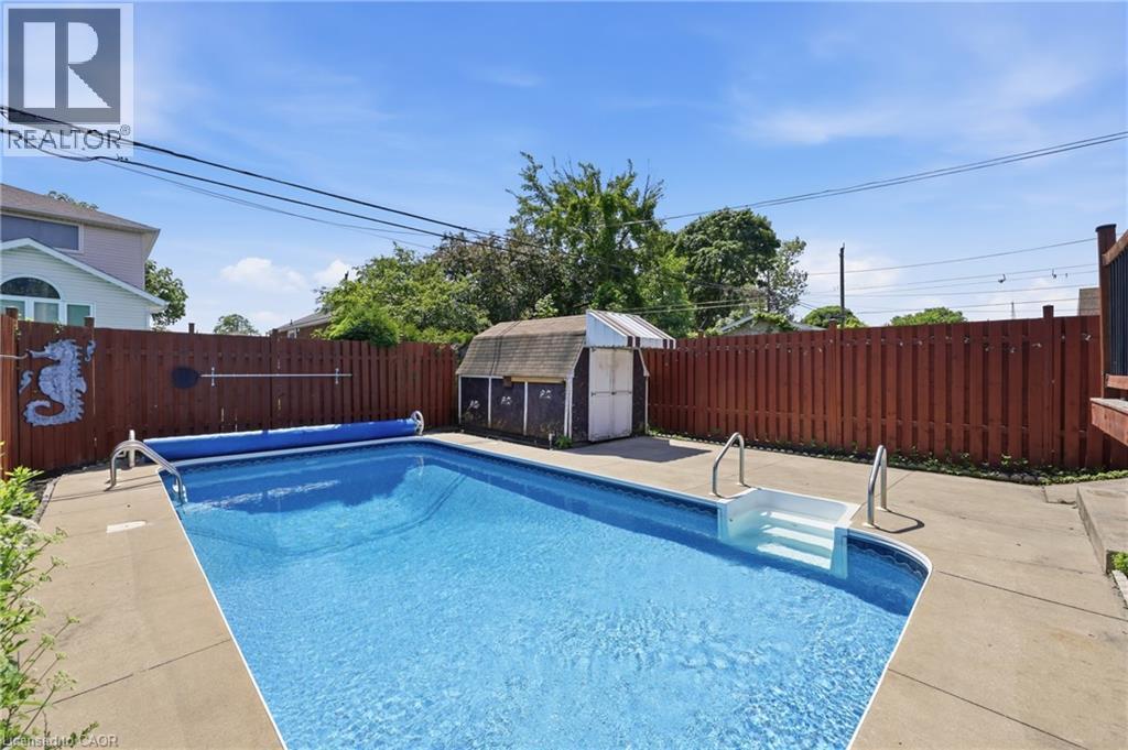 Fenced backyard featuring an in-ground swimming pool with concrete surround - 97 Tragina Avenue S, Hamilton, ON