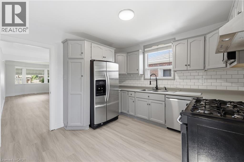 Kitchen featuring light gray cabinetry, white subway tile backsplash, stainless steel appliances, and a gas range - 97 Tragina Avenue S, Hamilton, ON