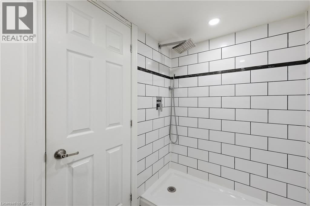 Shower with white subway tile walls, black grout, and a black accent tile stripe - 97 Tragina Avenue S, Hamilton, ON