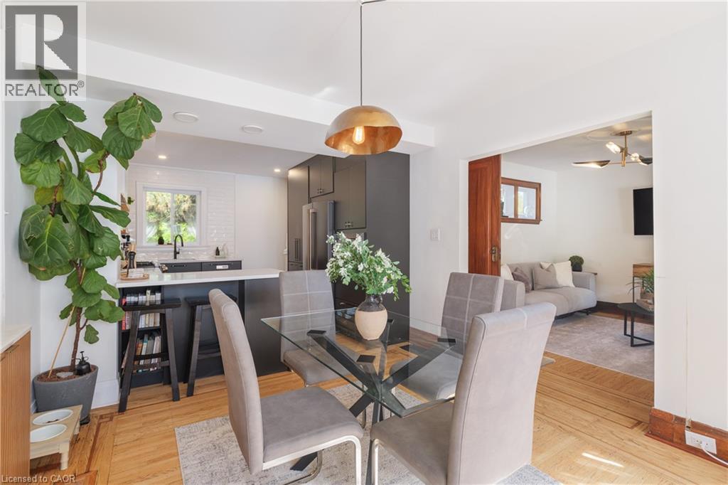 Dining area featuring hardwood flooring with inlay details and a contemporary brass pendant light - 41 Park Row N, Hamilton, ON