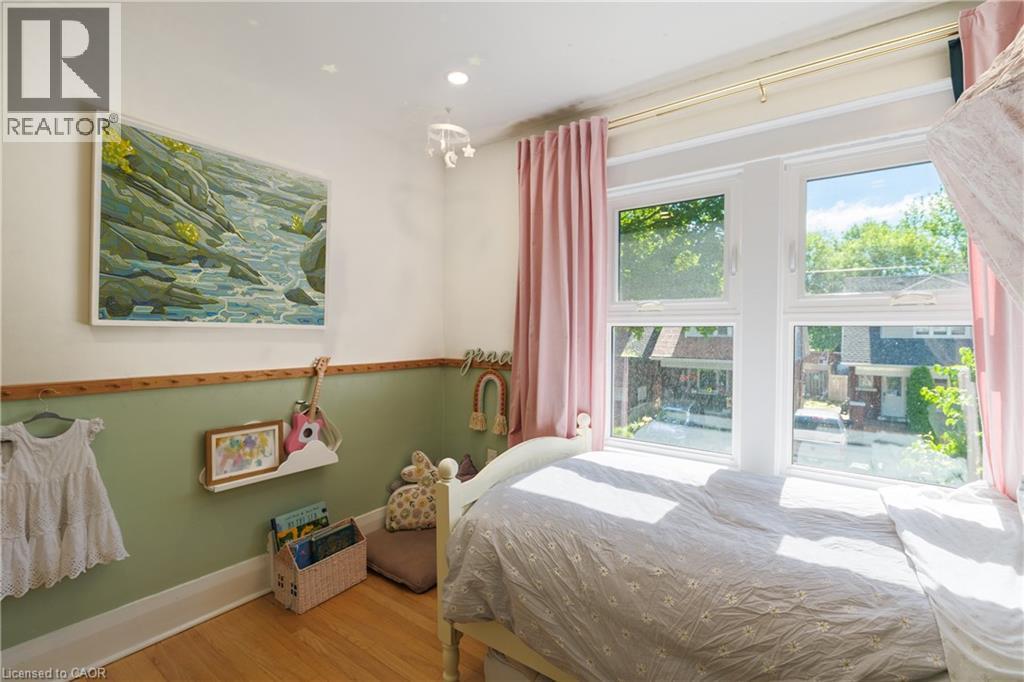 Bright room featuring a multi-pane window, wood-finish flooring, and a two-tone wall with wainscoting - 41 Park Row N, Hamilton, ON