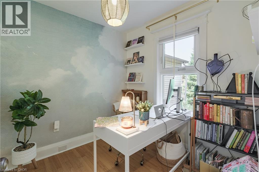 Room featuring wood-finish flooring, a decorative wall covering, a single window, white baseboards, and two built-in wall shelves - 41 Park Row N, Hamilton, ON