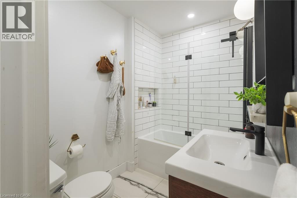Bathroom featuring a tub/shower combination with subway tile surround and a glass partition - 41 Park Row N, Hamilton, ON