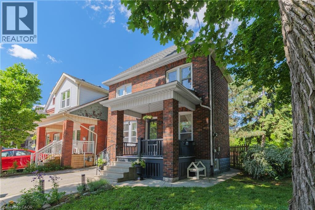 Two-story brick exterior featuring a covered front porch, white trim, and a gabled roof - 41 Park Row N, Hamilton, ON