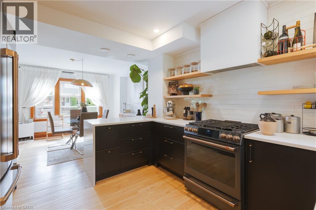 Contemporary kitchen featuring dark cabinetry, light countertops, and a full suite of modern appliances - 41 Park Row N, Hamilton, ON