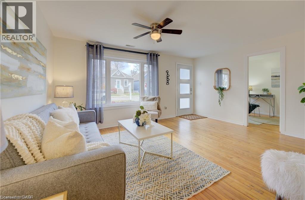 Bright living area featuring wood-finish flooring, a ceiling fan with integrated lighting, and a large window - 73 East 33Rd Street, Hamilton, ON