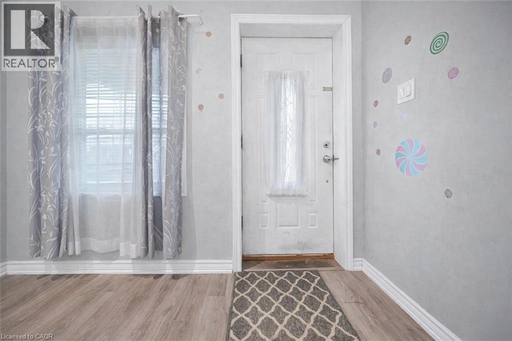 Entryway featuring a white paneled door with frosted glass insert, light wood-finish flooring, and white baseboards - 106 Lottridge Street, Hamilton, ON
