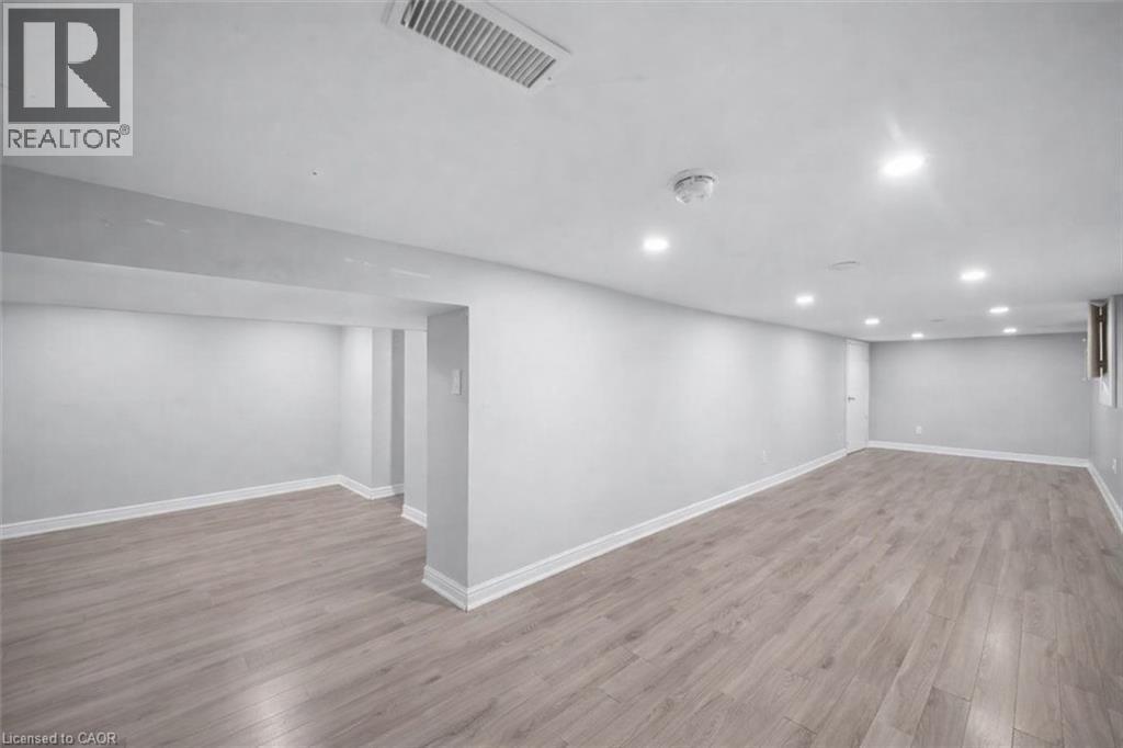 Spacious finished area featuring wood-finish flooring, recessed lighting, and crisp white trim - 106 Lottridge Street, Hamilton, ON