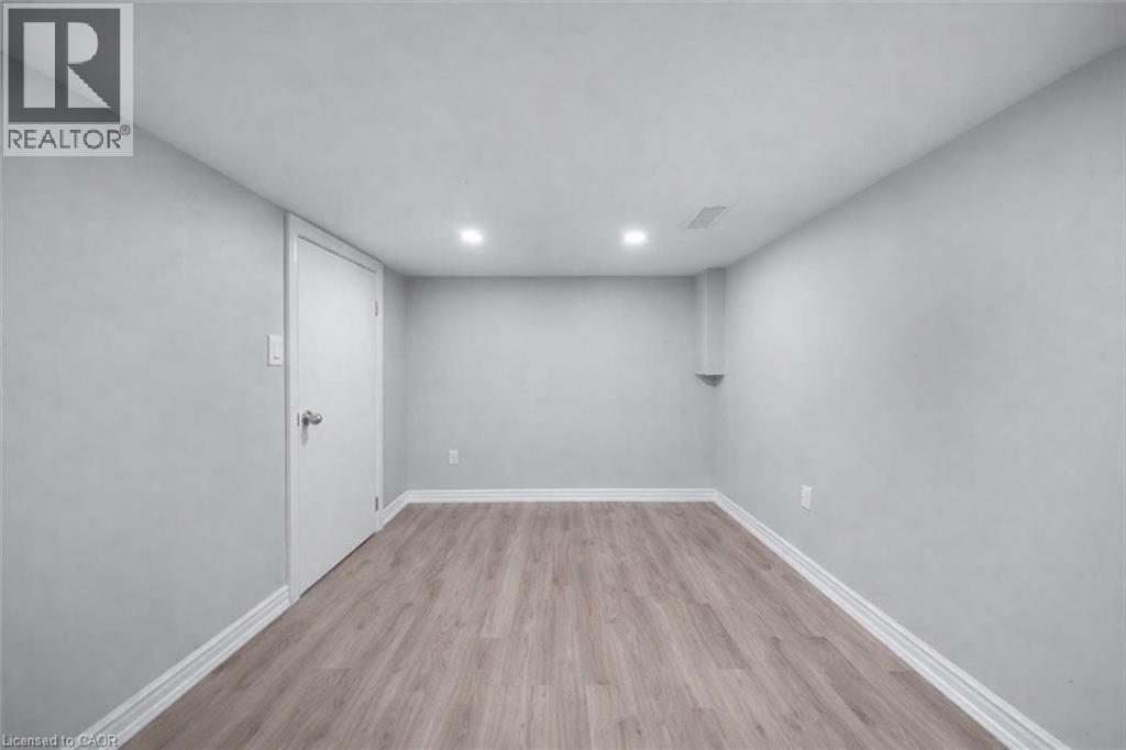 Bright room featuring light wood-finish flooring, recessed ceiling lighting, and crisp white baseboards - 106 Lottridge Street, Hamilton, ON