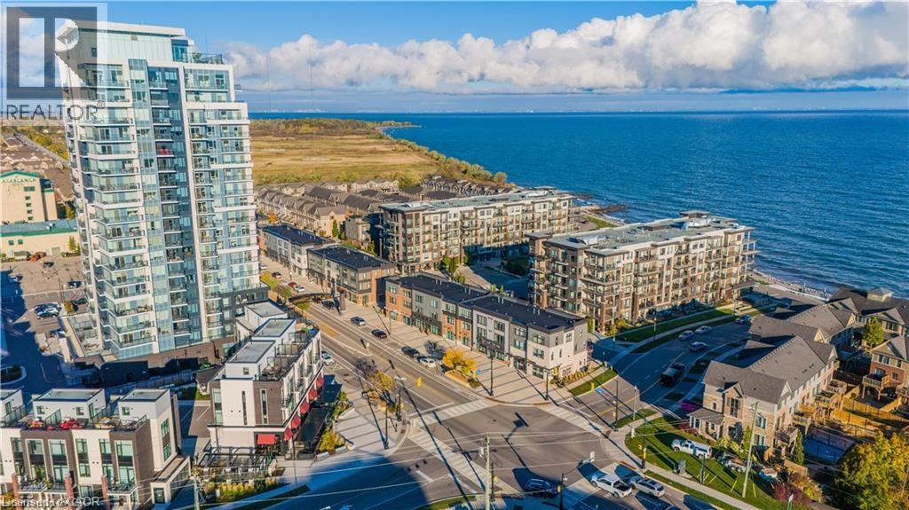 Modern high-rise residential building featuring expansive glass balconies and a prominent waterfront setting - 40 Esplanade Lane Unit# 614, Grimsby, ON