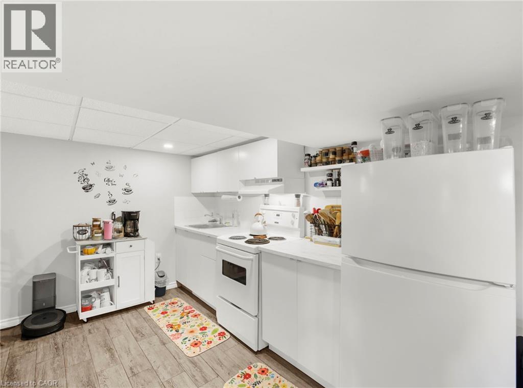 Kitchenette featuring wood-finish flooring, white cabinetry, white countertops, and white appliances - 420 Waverly Street, Hamilton, ON