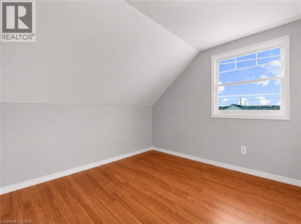Room featuring wood-finish flooring, a window with divided lites, and sloped ceiling details - 420 Waverly Street, Hamilton, ON