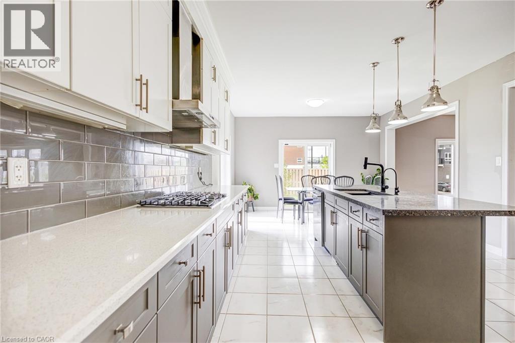 Modern kitchen featuring white upper cabinetry, gray lower cabinetry, and a gray subway tile backsplash - 417 Rivertrail Avenue, Kitchener, ON
